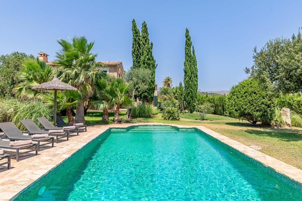 a swimming pool in a yard with chairs and trees at Villa Can Paroya in Alcudia