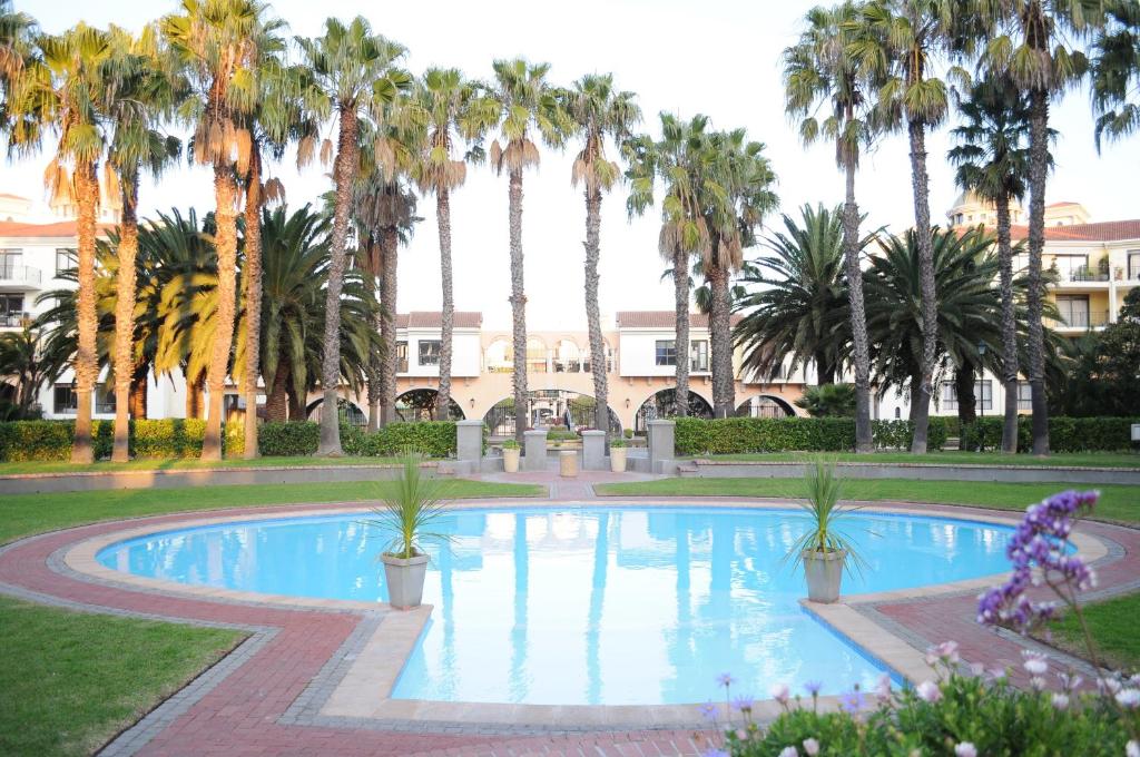 une piscine avec des palmiers et un bâtiment en arrière-plan dans l'établissement Luxury 2 bedroom apartment in Cape Town, au Cap