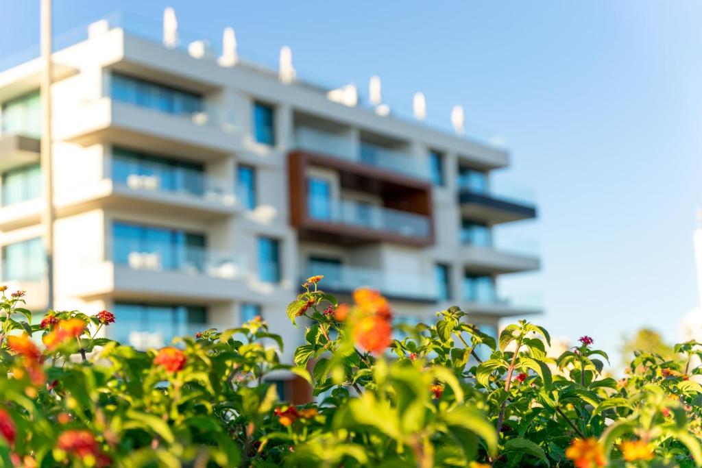 un grand immeuble situé derrière une brousse avec des fleurs dans l'établissement Shantivillas Portimão, à Portimão