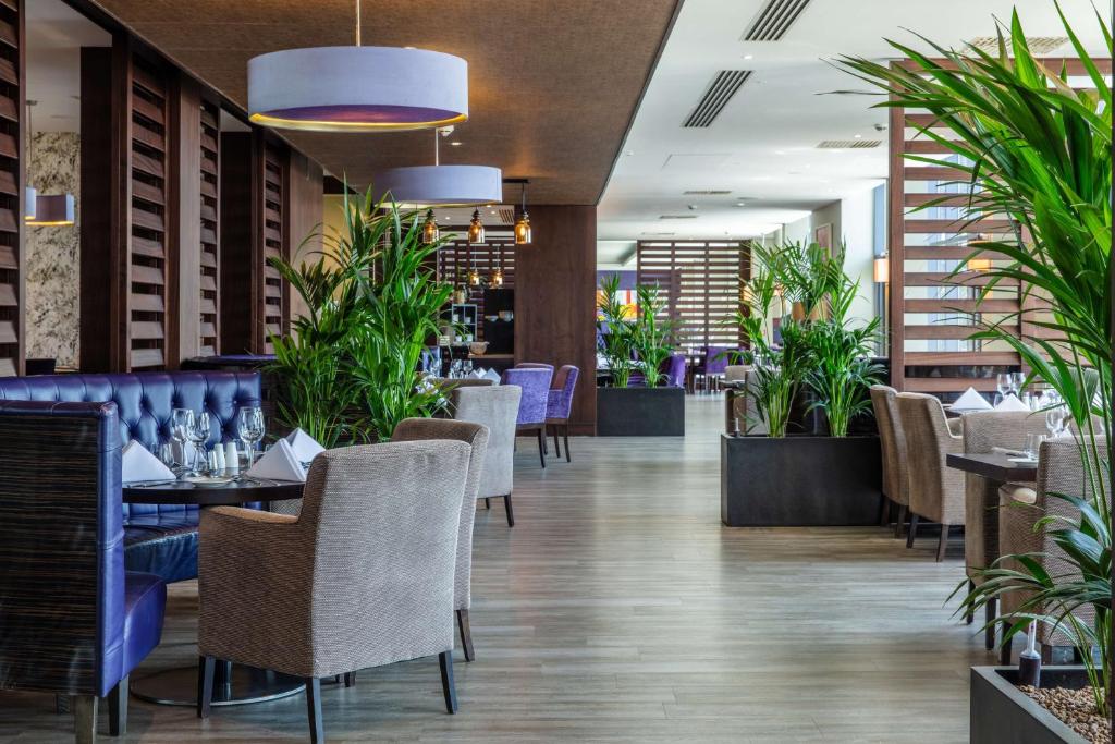 a restaurant with tables and chairs and plants at Radisson Blu Waterfront Hotel, Jersey in Saint Helier Jersey