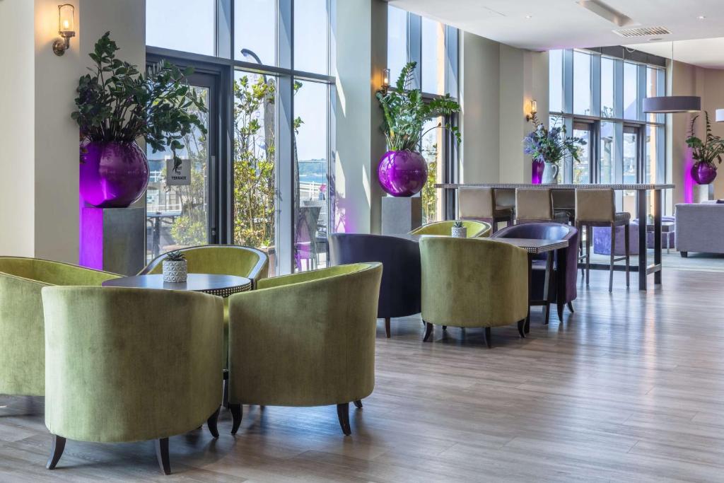 a restaurant with tables and chairs and windows at Radisson Blu Waterfront Hotel, Jersey in Saint Helier Jersey