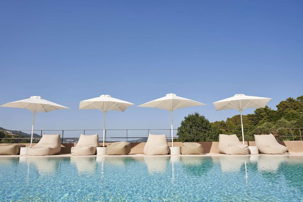 una fila di sedie e ombrelloni bianchi accanto alla piscina di Radisson Resort Plaza Skiathos a Kanapitsa