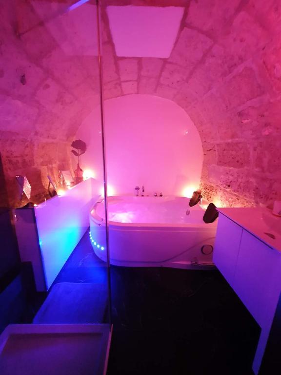 La salle de bains est pourvue d'une baignoire blanche avec des lumières violettes. dans l'établissement LA FORTERESSE - Jacuzzi/Sauna - Centre Historique, à Rouen