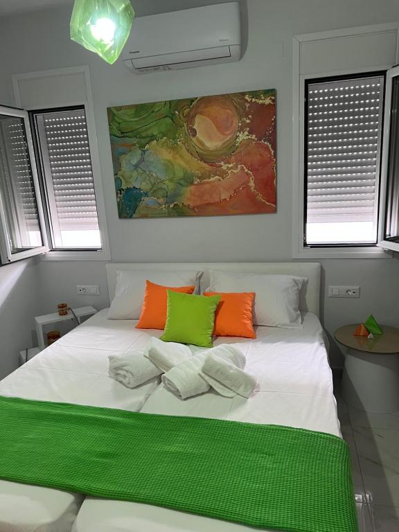 una camera da letto con un letto bianco con cuscini verdi e arancioni di Longbeachvillas 2 Thesia beachfront villa a Makris Gialos