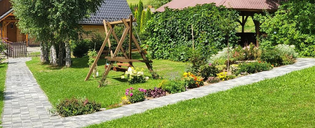 a garden with a wooden swing in the grass at Cichy Zakątek in Uście Gorlickie