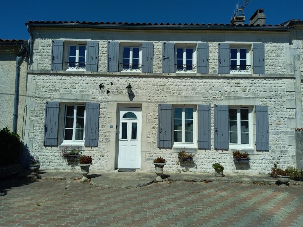 budynek z białej cegły z niebieskimi okiennicami i drzwiami w obiekcie Gîte climatisé les hirondelles w mieście Pons