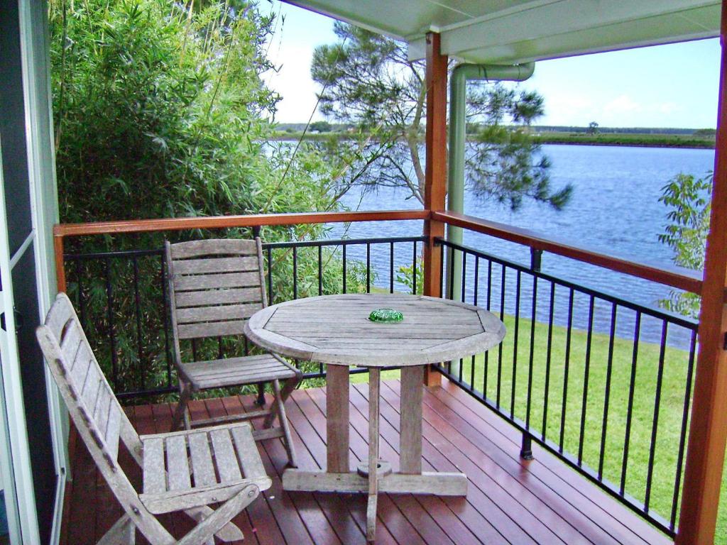 a table and two chairs on a porch with a view of the water at Coast and Country Cabin 4 