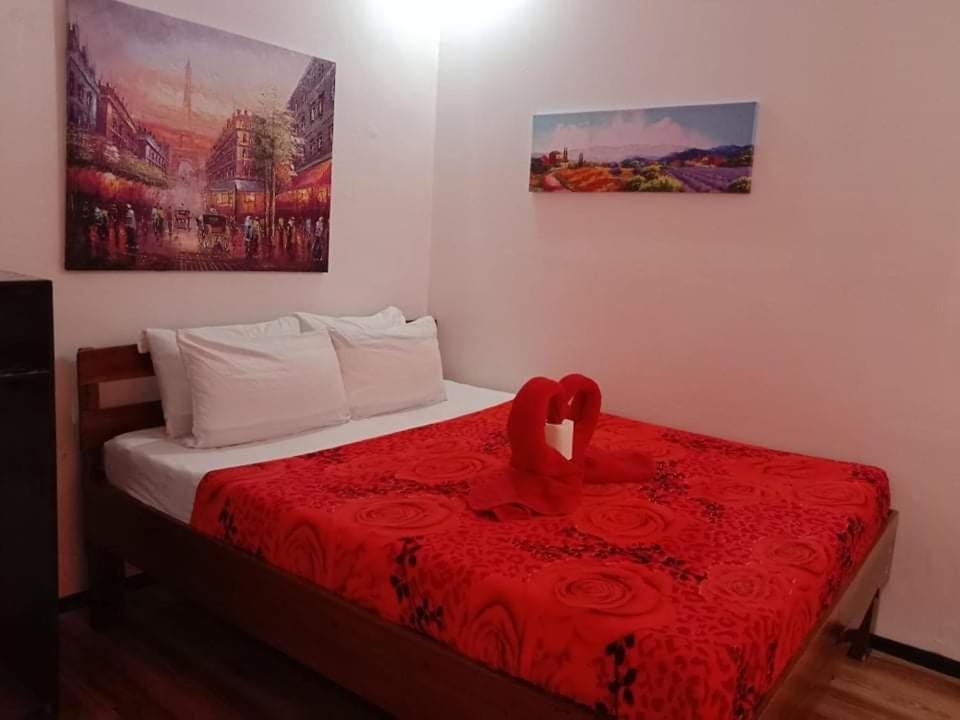 a bedroom with a bed with a red blanket and roses at KIMURA PENSION in El Nido