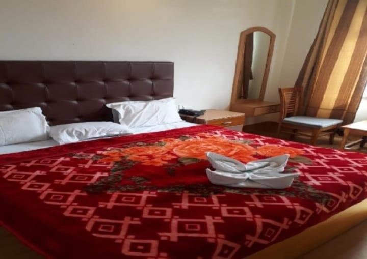 a bed with a red bedspread with two dishes on it at Krishna Guest House By WB Inn in Agra