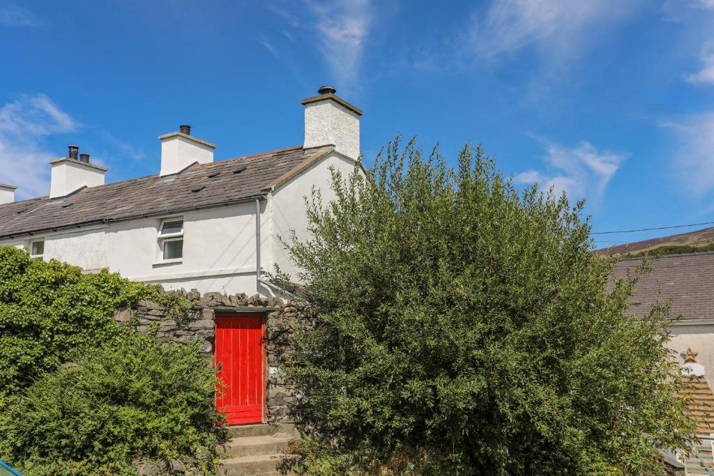 a white house with a red door at Ty Bach - Llanberis in Caernarfon
