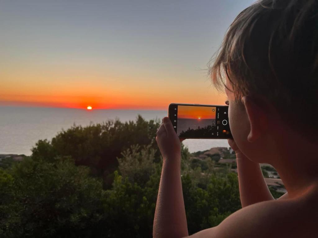 una mujer tomando una foto de la puesta de sol en Casa Faedda Costa Paradiso, en Costa Paradiso