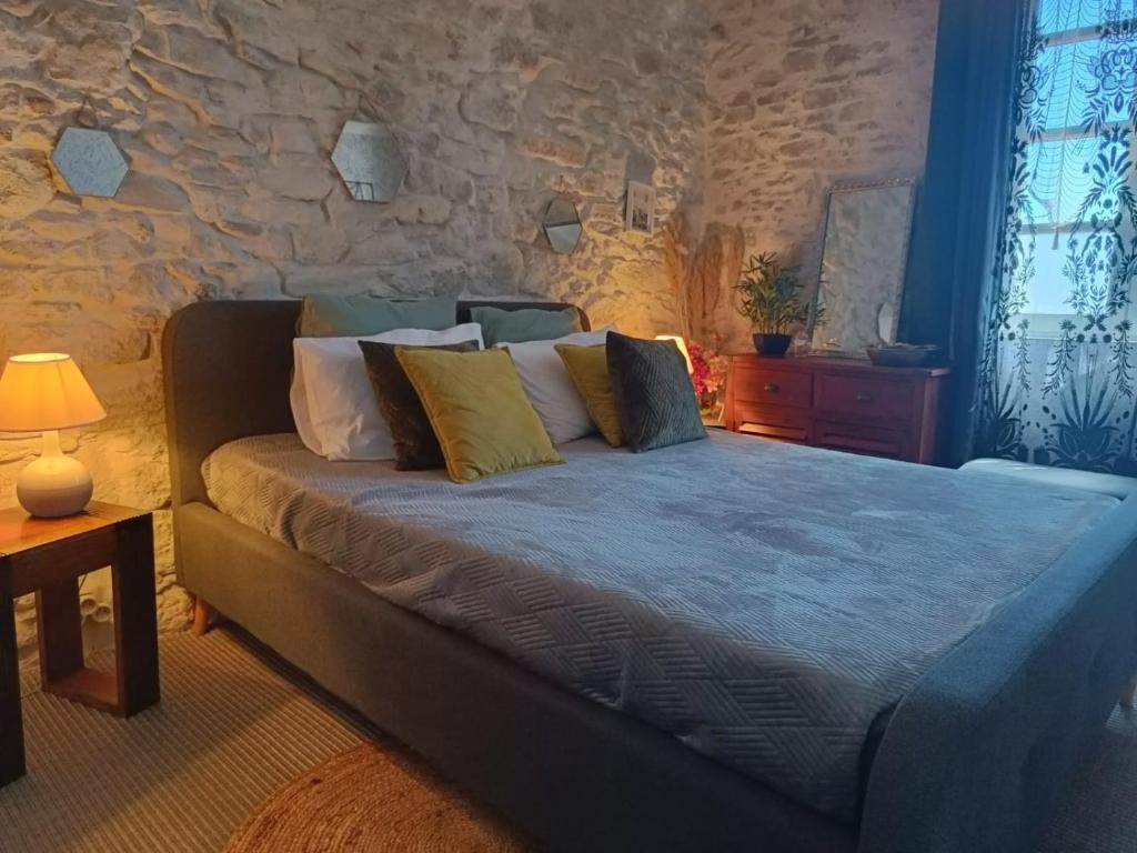 a bedroom with a bed with pillows and a stone wall at Entre Bastide et Cité in Carcassonne