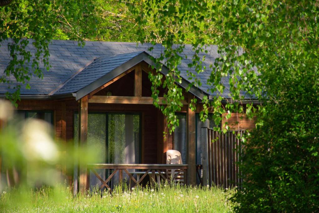 un homme assis à une table devant une maison dans l'établissement Les Chalets de Booz, à Saint-Germain-du-Teil