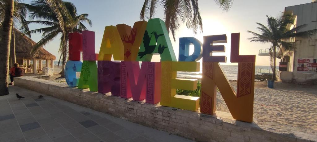 a colorful sign on a wall next to the beach at Calaveritas Rooms in Playa del Carmen