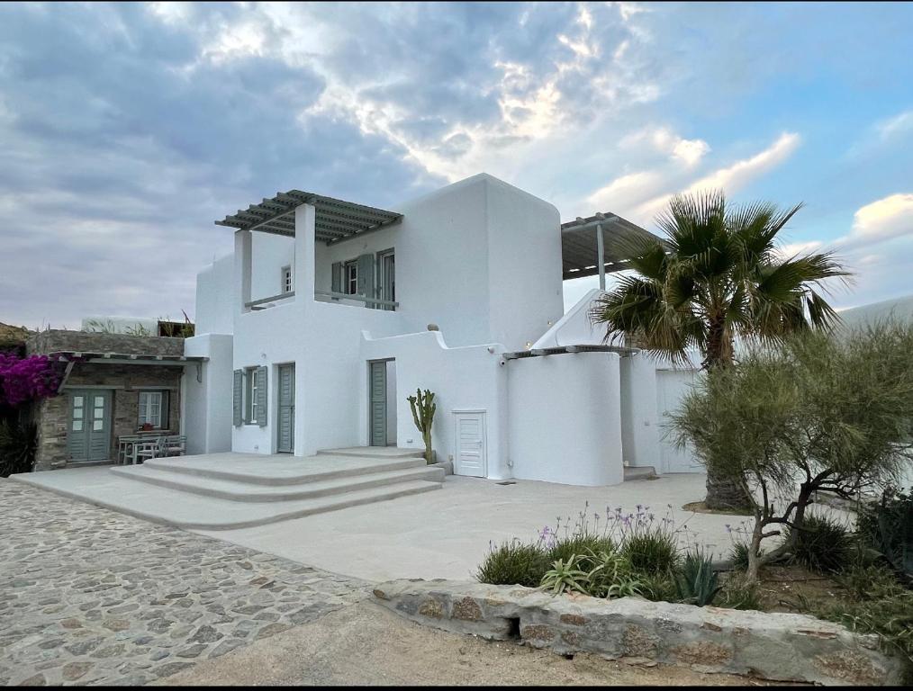 a white house with a palm tree in front of it at Mykonos Cocooning in Panormos Mykonos