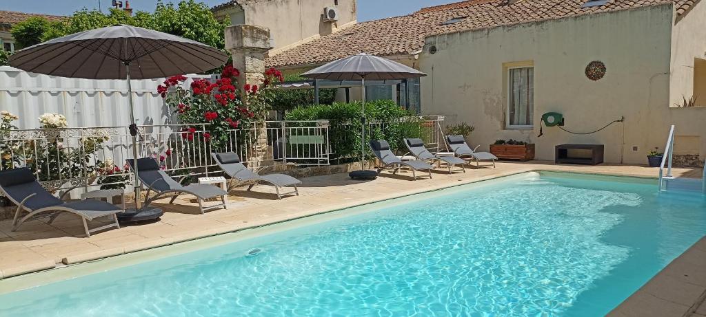 a pool with chairs and umbrellas next to a house at Lacanepière in Générac