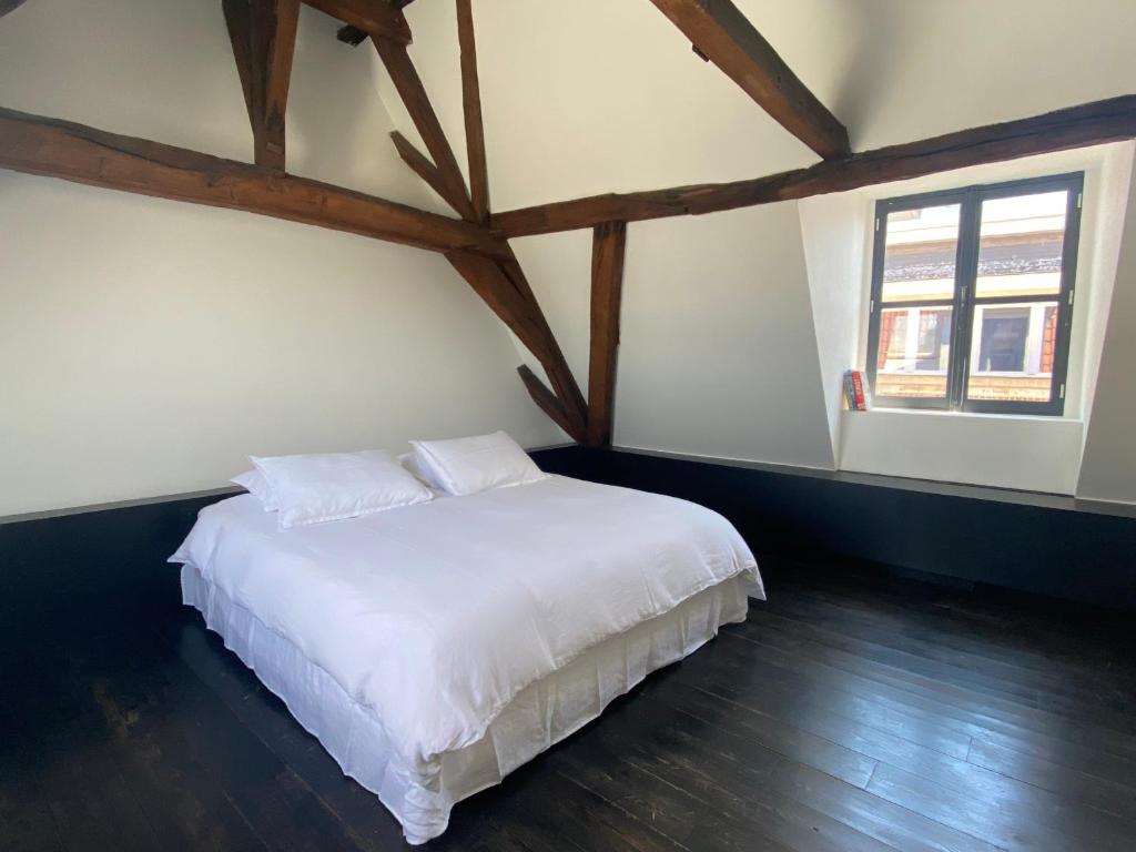 una camera da letto con un letto con lenzuola bianche e due finestre di ANNA a Gand