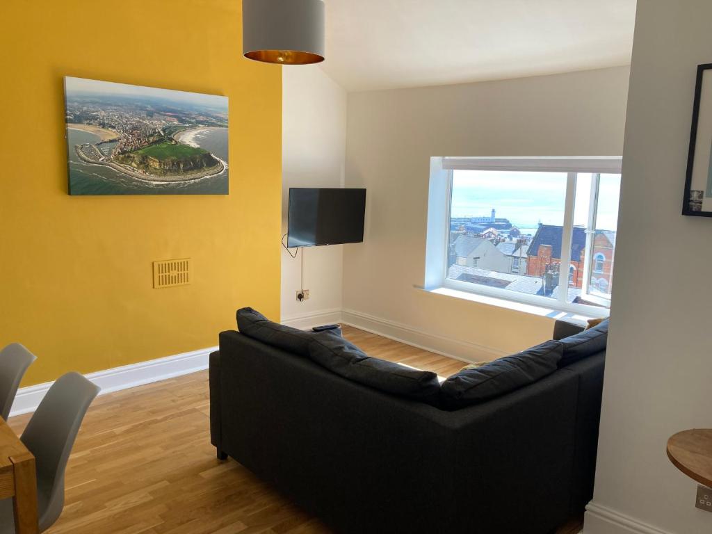 a living room with a black couch and a window at The View Apartments Castle Road in Scarborough