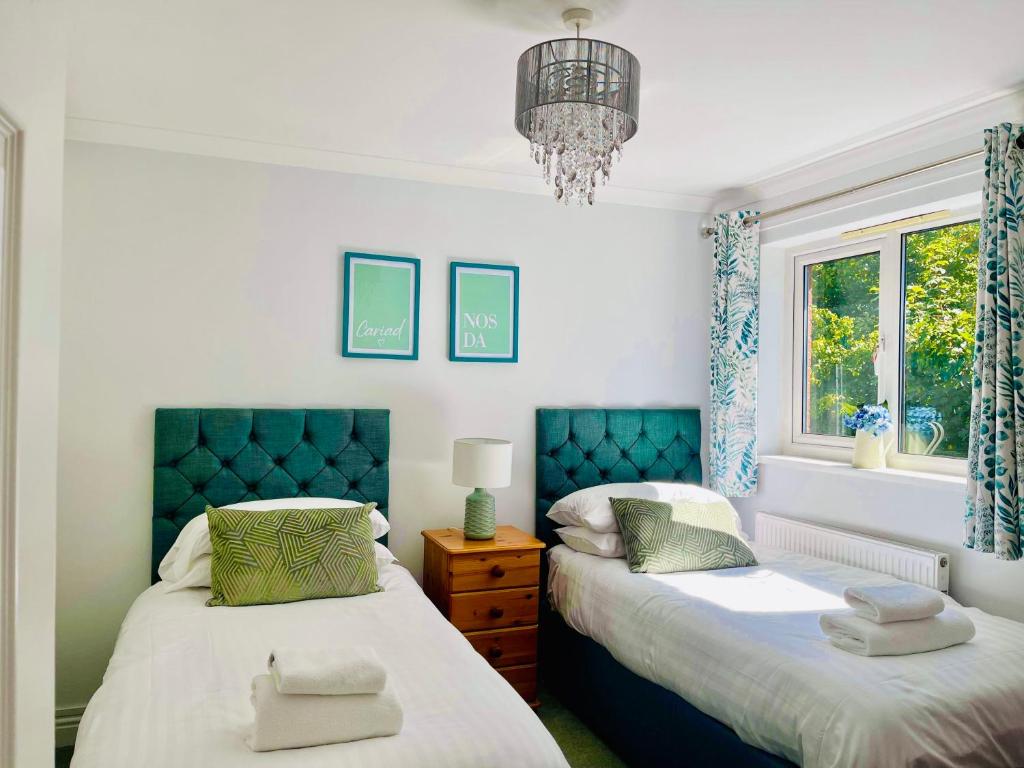 a bedroom with two beds and a chandelier at Tanglewood house Abergavenny with private parking in Abergavenny