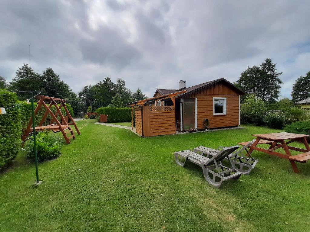 a cabin with a picnic table and a playground at Domek Drewniany 2 in Lubiatowo