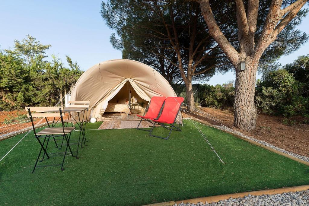 namiot z dwoma krzesłami i stołem przed nim w obiekcie Glamping La Mimosa CONIL w mieście Conil de la Frontera