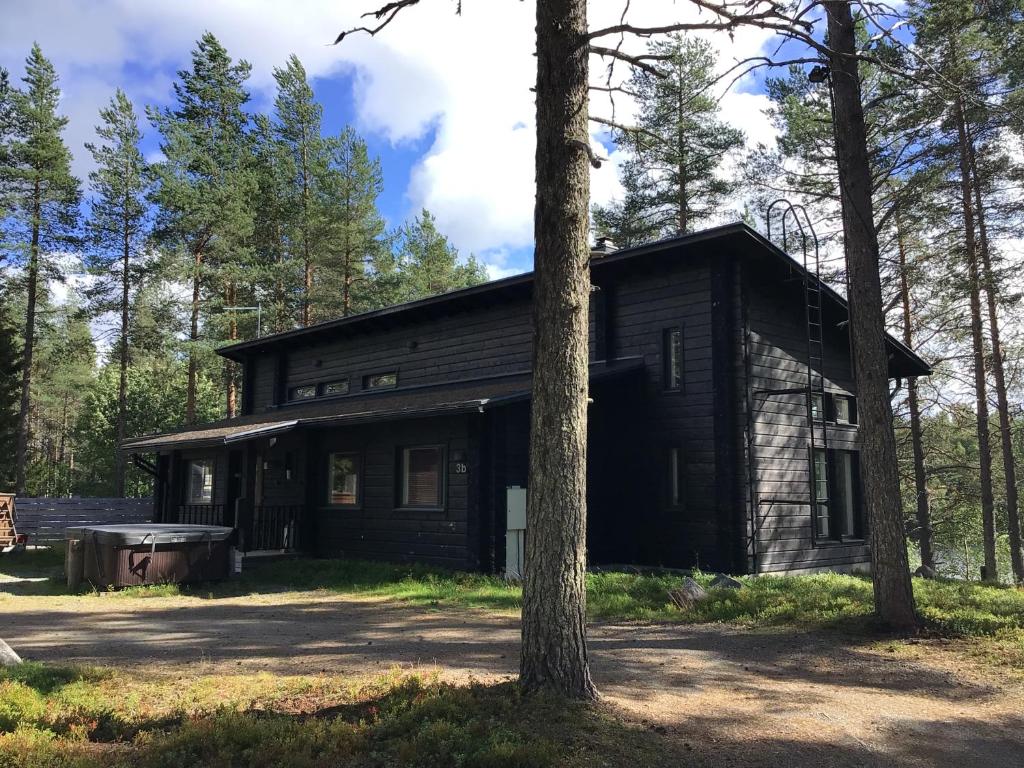 eine Blockhütte im Wald mit einem Baum in der Unterkunft Kuhmit cottages in Kuusamo