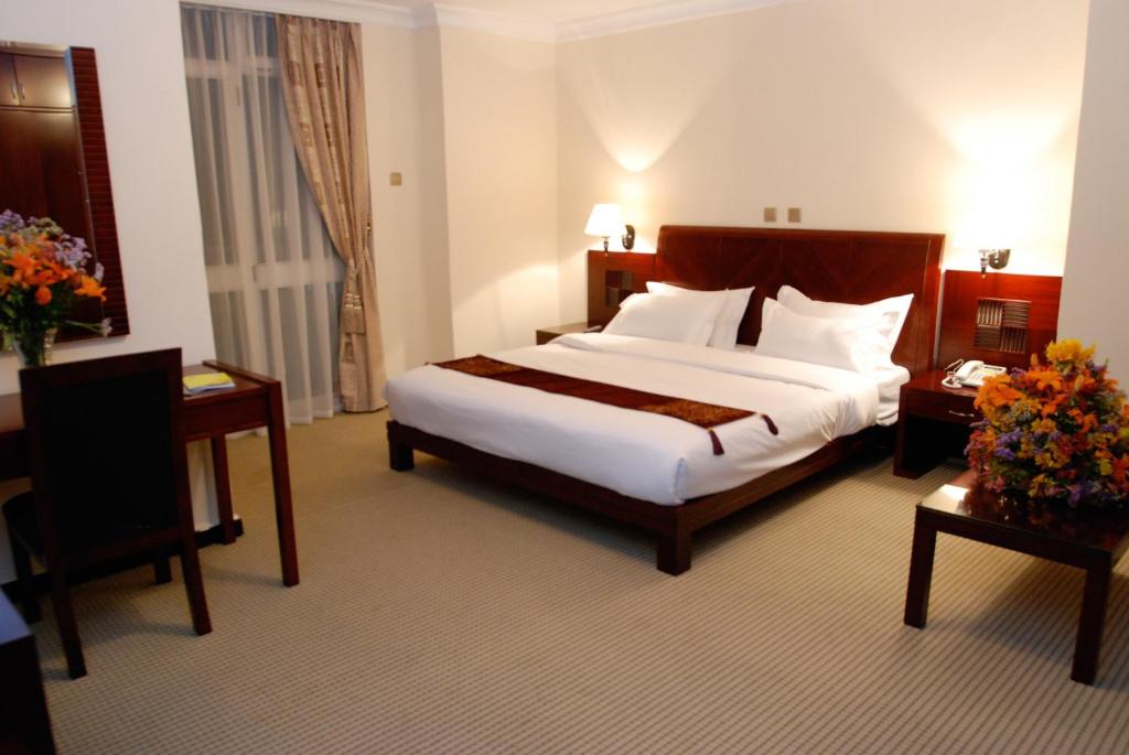 pokój hotelowy z dużym łóżkiem i dwoma stołami w obiekcie Kaleb Hotel w Addis Abebie