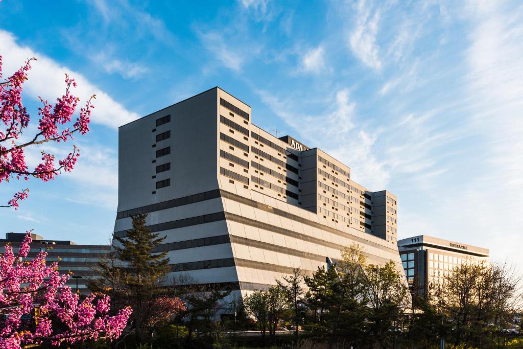 een hoog gebouw met roze bloemen ervoor bij APA Hotel Woodbridge in Iselin