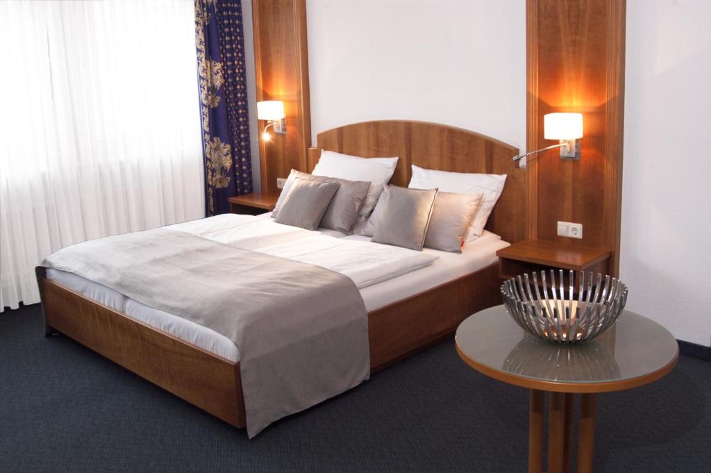 a bedroom with a large bed and a table at Hotel Germania in Reutlingen