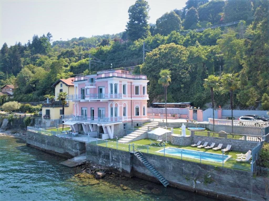 une grande maison rose assise sur l'eau dans l'établissement Luxury Villa Olga in Stresa, à Baveno