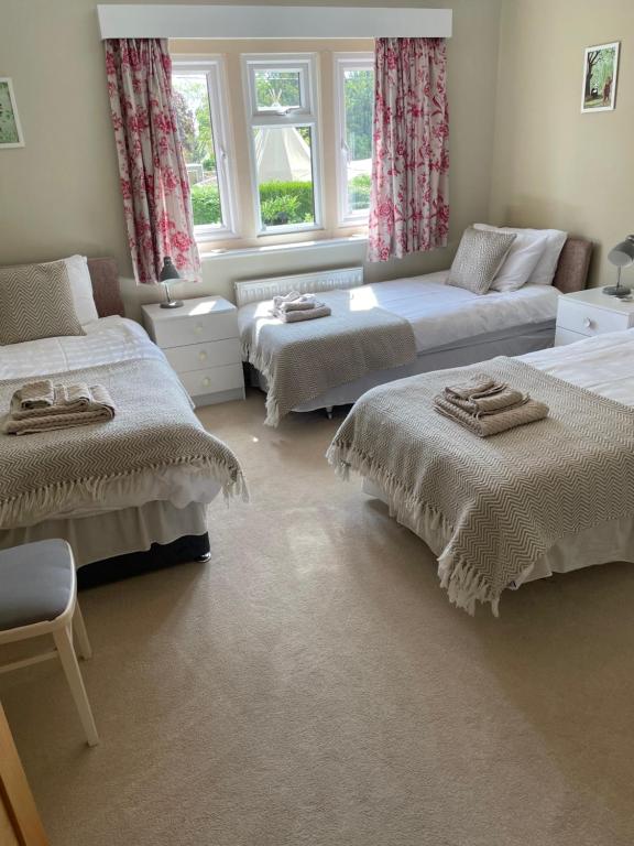 a bedroom with two beds and a couch and windows at Cotswolds Luxury House in Central Bourton Large Sleeps 2-11. Pet Friendly. in Bourton on the Water
