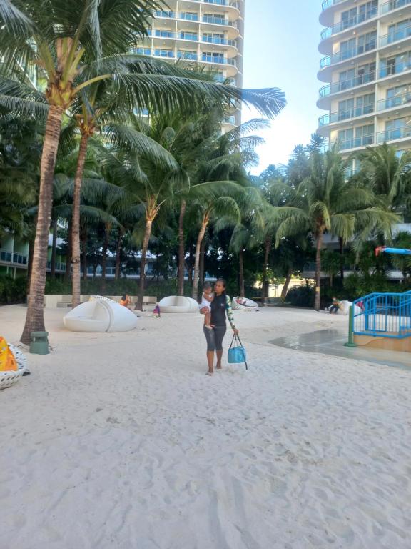 a woman standing on a beach with palm trees at Azure Condotel in Manila