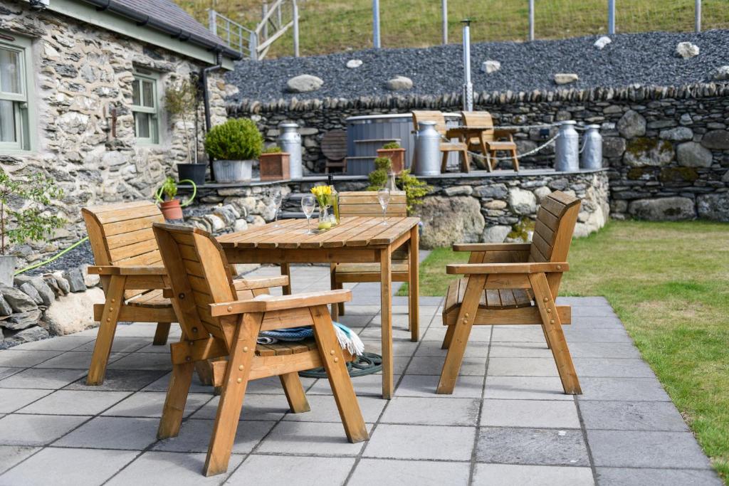 een houten tafel en stoelen op een patio bij Finest Retreats - Moelis Granary - Luxury Cottage with Hot Tub in Llandrillo