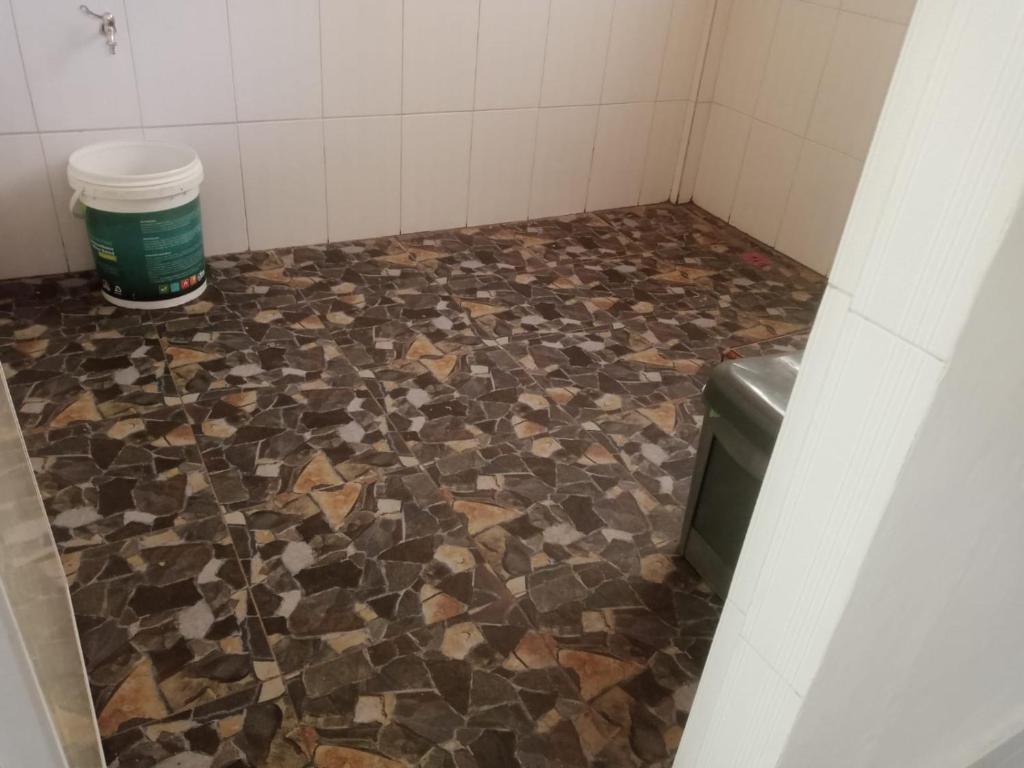 a bathroom with a tiled floor with a trash can at Raja Guest House - Jungle Trekking & Tours Bukit Lawang Sumatra in Bukit Lawang