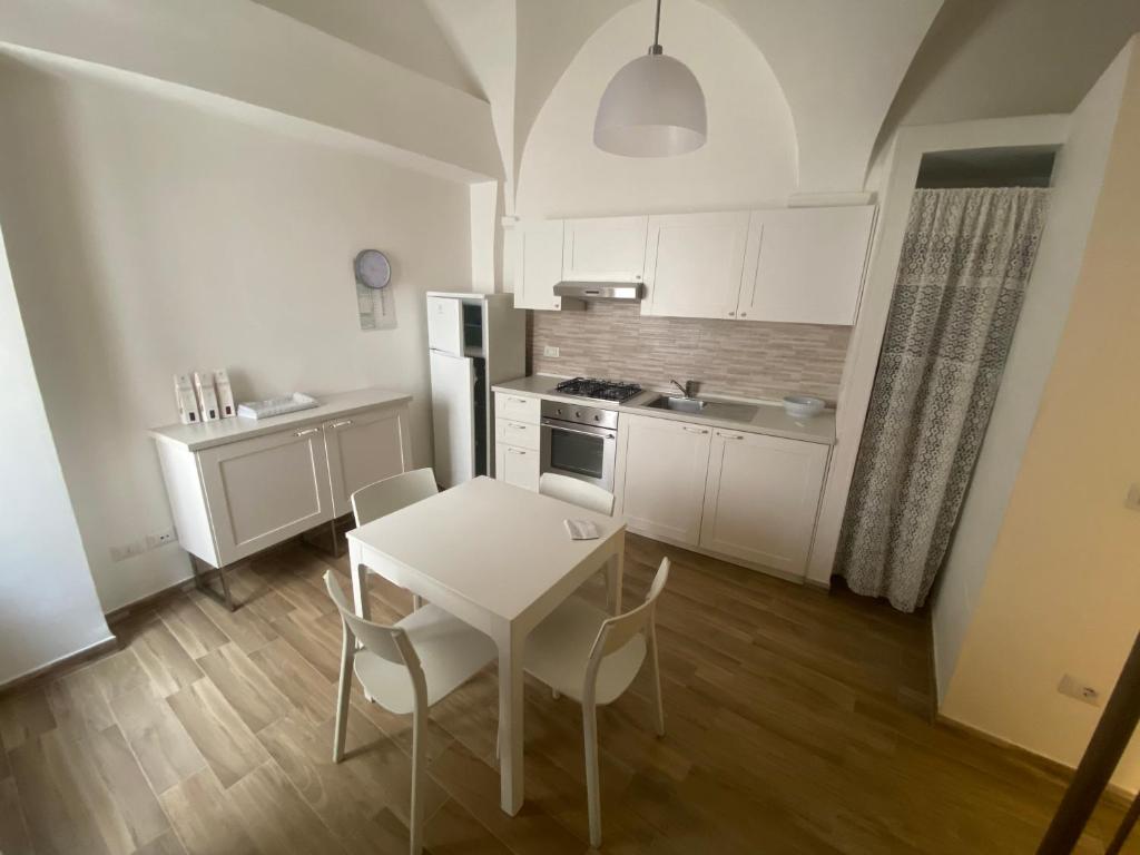 - une cuisine avec une table et des chaises blanches dans la chambre dans l'établissement La Chianca, à Putignano