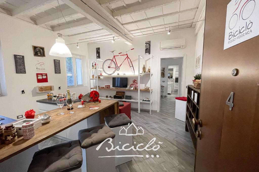 a large room with a table and a room with a bike on the wall at Biciclo' Rosso Ferrara in Ferrara