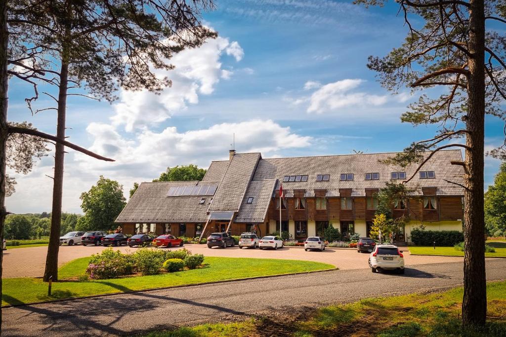 a large building with cars parked in a parking lot at Abzali Hotel and Restaurant with self check-in in Ādaži