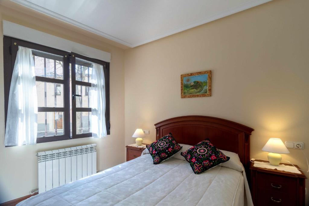 a bedroom with a bed with two pillows and a window at El Jardín de Fray Diego in Zamora