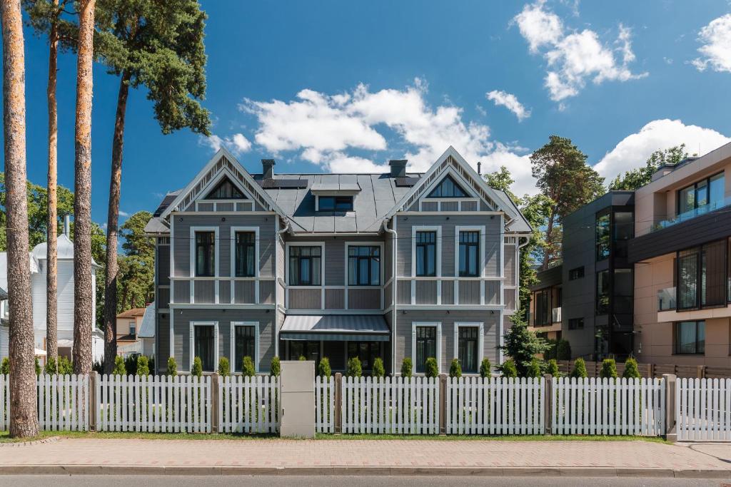 a gray house with a white fence at Jurmala Apartment LUX in Jūrmala