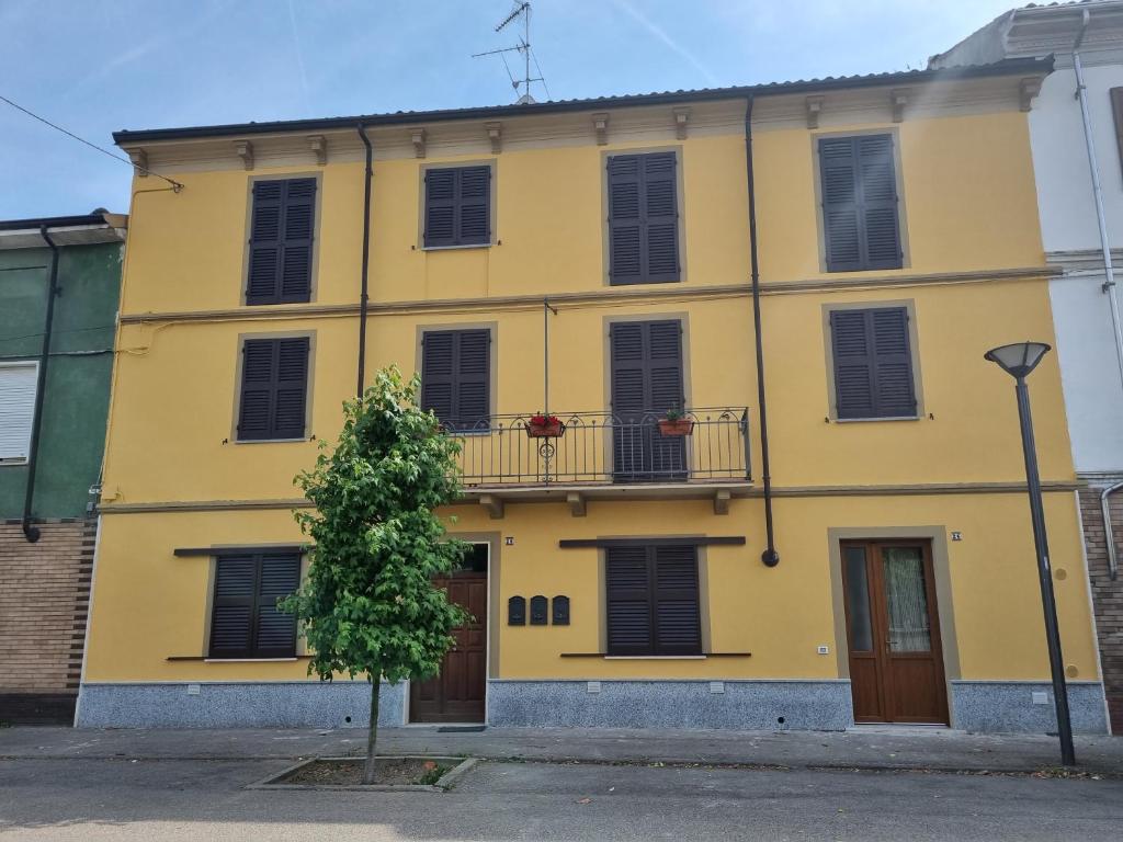 a yellow building with a balcony and a tree at La Casa di Dedè in Sale