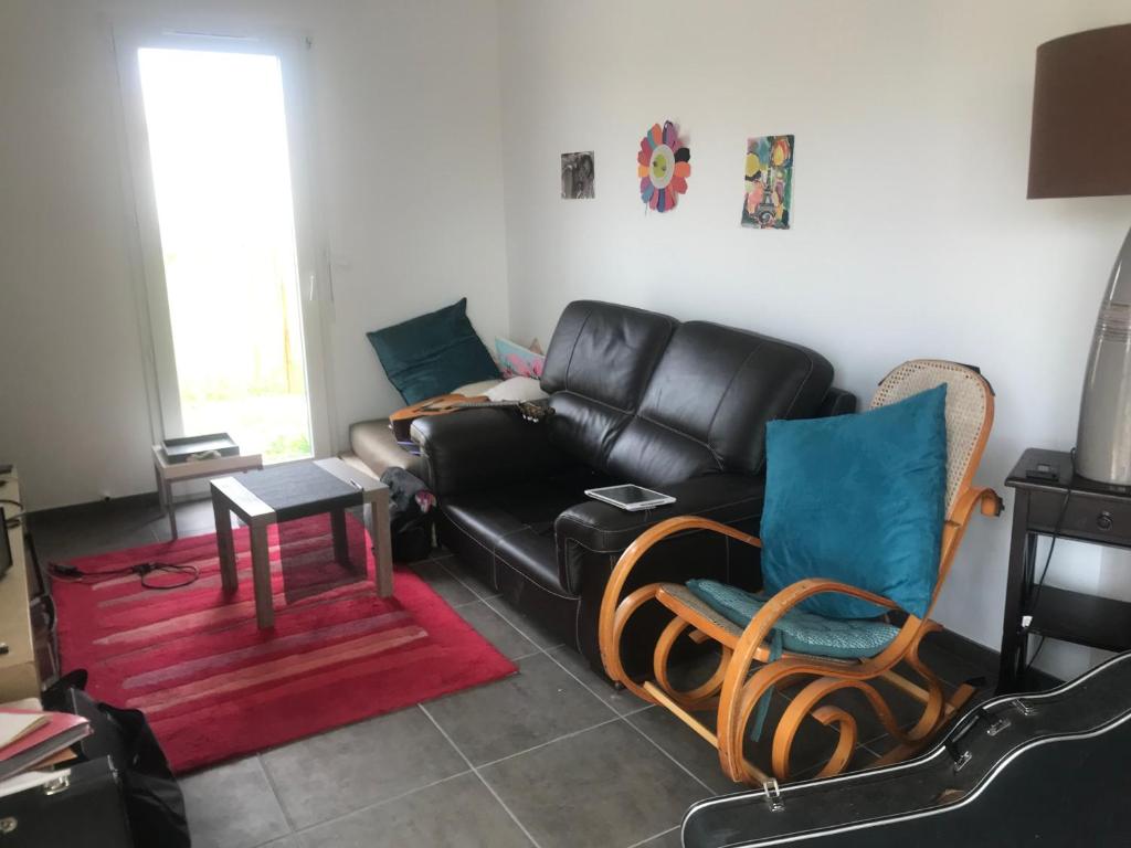 uma sala de estar com um sofá de couro preto e cadeiras em Charmante maison Toutes commodités em Auros