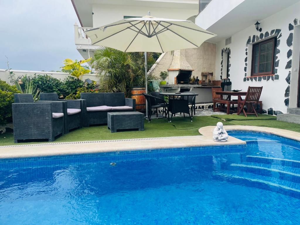 una piscina con sombrilla junto a una casa en Pintadera´s house/Tara, en Icod de los Vinos