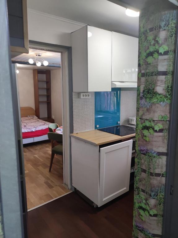 a kitchen with white cabinets and a room with a bed at Studio indépendant dans un maison in Saint-Denis