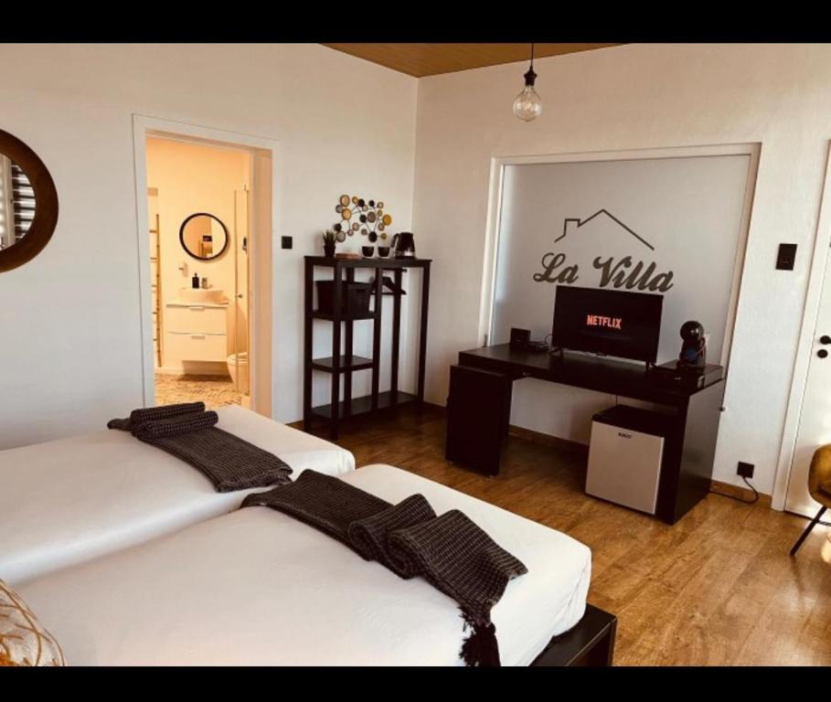 1 dormitorio con 2 camas, escritorio y TV en La Villa Bastogne chambre d'hôtes 1 en Bastogne