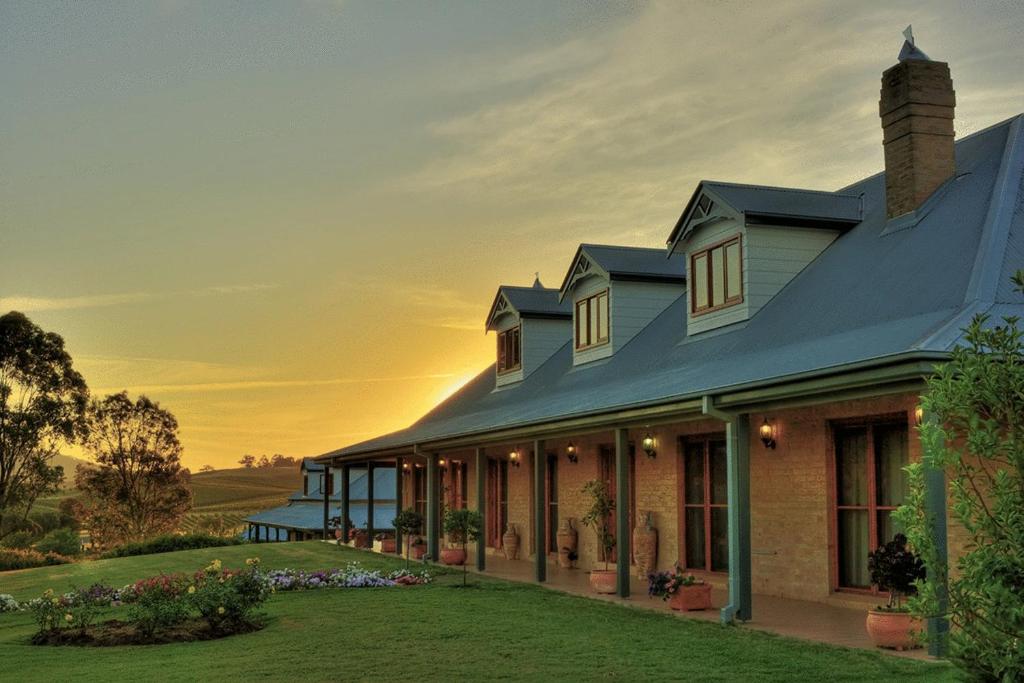 a house with the sunset in the background at Berenbell Vineyard Retreat in Pokolbin
