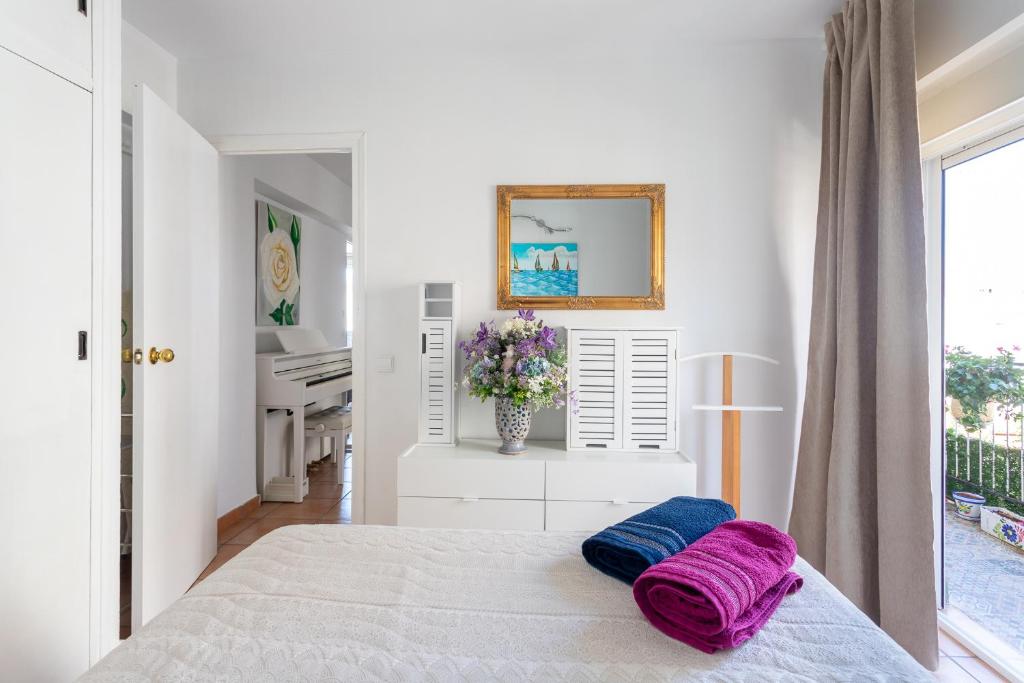 um quarto branco com uma cama com almofadas roxas em Cozy apartment in the center of Benidorm! em Benidorm
