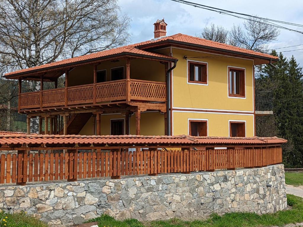 a house with a balcony on top of a stone wall at Къща за гости Феникс in Koprivshtitsa