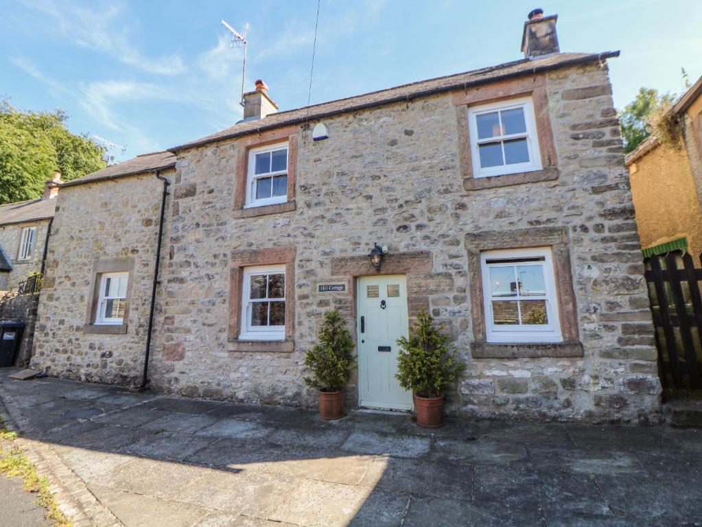 an old stone house with a white door at Hill Cottage in Matlock