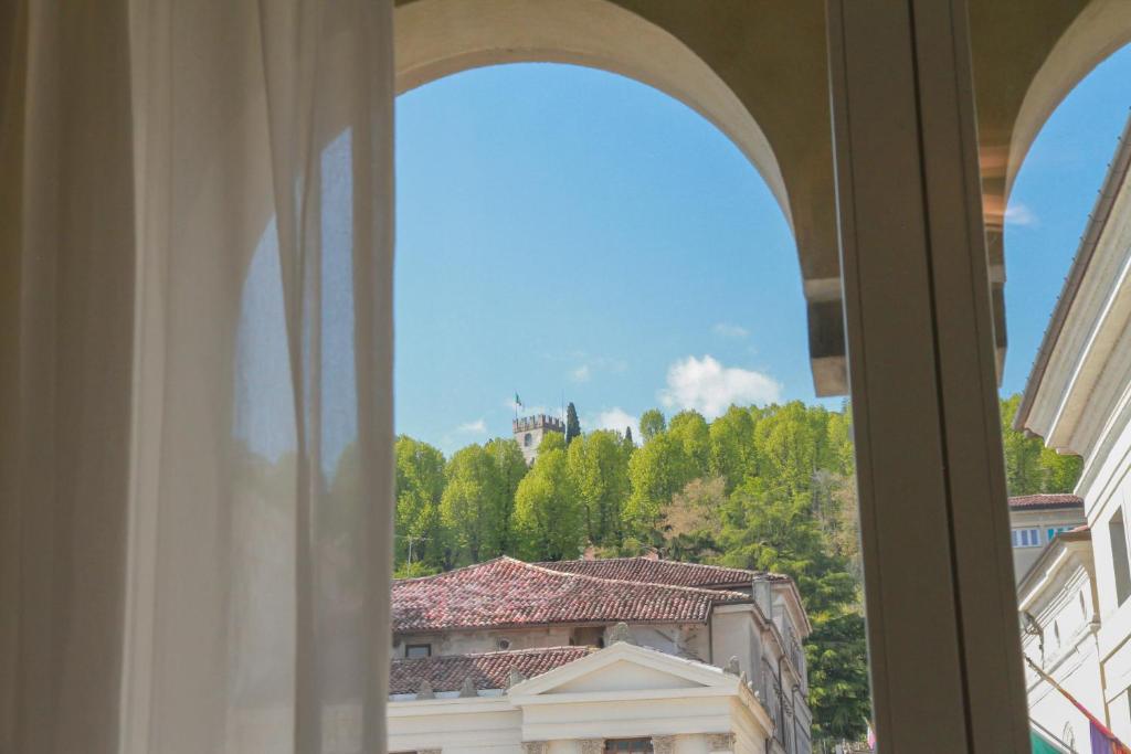 a window with a view of a building and trees at Locanda Mezzosale in Conegliano