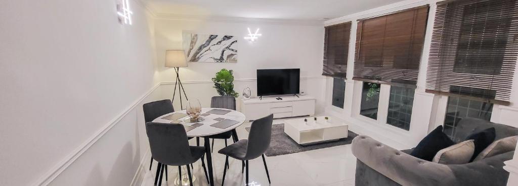 ein Wohnzimmer mit einem Tisch, Stühlen und einem TV in der Unterkunft Stunning 2 bedroom apartment in Canary Wharf - Morland Apartments in London